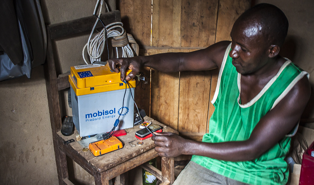 Bonde med Mobisolbatteri på den rwandiska landsbygden.